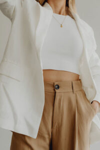 Cropped woman wearing a basic white shirt with white blazer and brown trousers