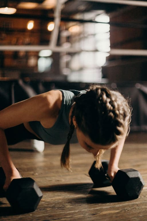 A cropped woman doing weighted pushups