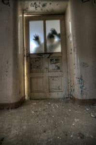 A figure behind an old door in a haunted hallway