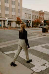 A woman walking across a pedestrian crossing outside her work building