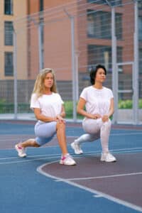 Two women lunge walking.