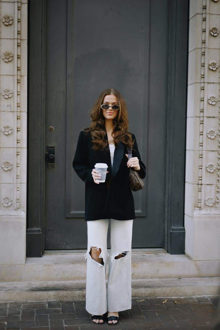 A woman wearing an oversized black blazer with wide-leg denim
