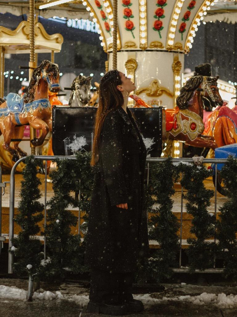 A woman standing in front of a merry-go-round