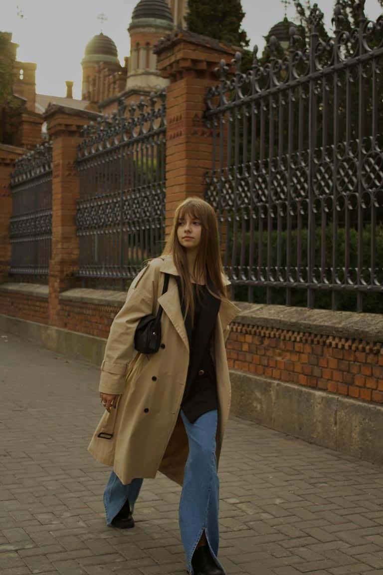 A woman wearing a beige trench coat with jeans