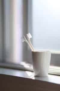 A pair of toothbrushes in a white cup.