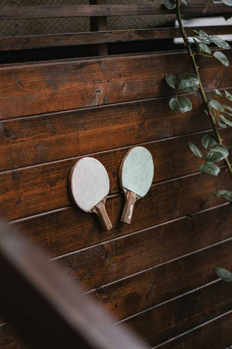 Two white table tennis bats mounted on a wooden wall